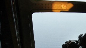Un oficial de las fuerzas aéreas de Malasia busca en el mar los escombros del avion de la aerolínea de Malasia desaparecido.
