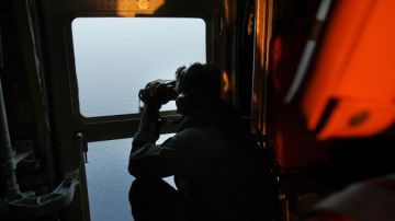 Un oficial de las fuerzas aéreas de Malasia busca en el mar los escombros del avion de la aerolínea de Malasia desaparecido.