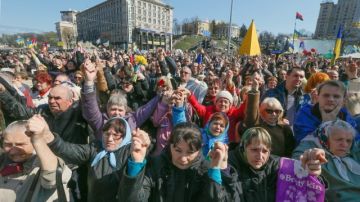 Ucranianos se dan la mano durante una reunión de réquiem por el eterno descanso de las almas de las personas asesinadas durante las protestas masivas.