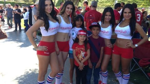 Seguidores de Chivas USA son acompañados paran la foto por guapas edecanes.