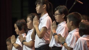 Un grupo de niños reza durante una misa budista  por los pasajeros que iba en vuelo de Malaysian Airlines que desapareció hace casi un mes.