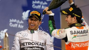 El piloto mexicano Sergio 'Checo' Pérez (izq.) baña en champaña al británico Lewis Hamilton, ganador del GP de Baréin de Fórmula 1.