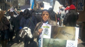 Raquel Navas sostiene un cartel que muestra las malas condiciones en que está su apartamento en el 98 de la calle Linden.