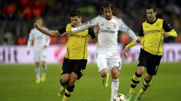 El lateral izquierdo portugués del Real Madrid Fabio Coentrao (c) lucha por el balón con el jugador del Borussia Dortmund Milos Jojic (i)