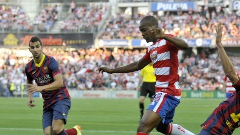 El defensor francés Foulquier (c), del Granada, trata de escapar de la marca de Sergio Busquets (d) del  Barcelona.