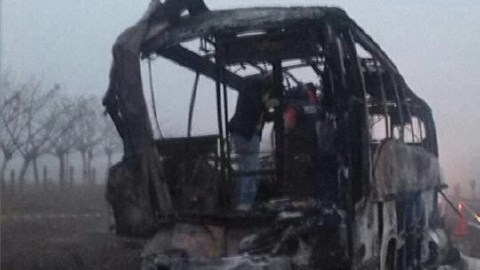 Un hombre inspecciona los restos del autobús turístico incendiado.