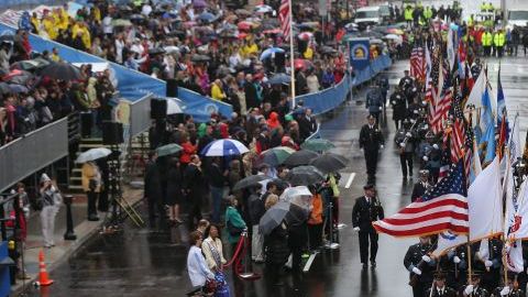 Miembros de una guardia de honor cruzan la línea de meta del maratón de Boston durante un tributo a las víctimas de los atentados de hace un año.
