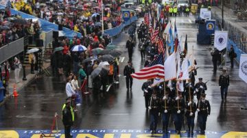 Miembros de una guardia de honor cruzan la línea de meta del maratón de Boston durante un tributo a las víctimas de los atentados de hace un año.