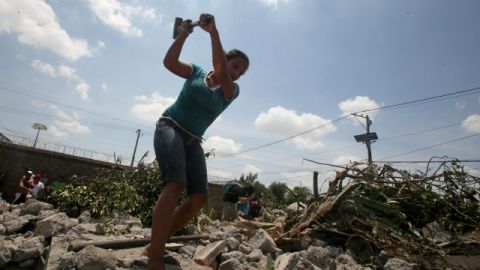 Una mujer extrae hierro de un área con escombros después de un sismo.
