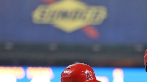 Albert Pujols es felicitado por  Mike Trout (izq.) y  Chris Ianetta tras conectar el cuadrangular 497.