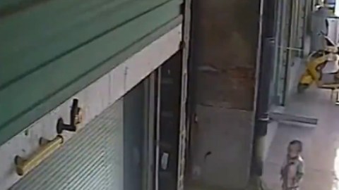 Antes de ser agredido, el niño se detiene en la puerta de un negocio y observa una aparente pelea en el interior.
