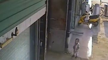 Antes de ser agredido, el niño se detiene en la puerta de un negocio y observa una aparente pelea en el interior.