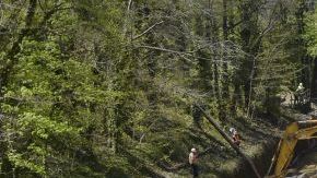 Máquinas retiran tierra y coches semienterrados  en un socavón que se abrió ayer en una calle de una zona residencial en Baltimore, Maryland, tras las lluvias.
