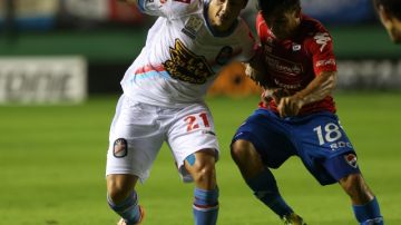 El jugador de Arsenal de Argentina, Federico Freire (izq.)  protege el balón ante el acoso de Derlis Orue, del Nacional paraguayo.