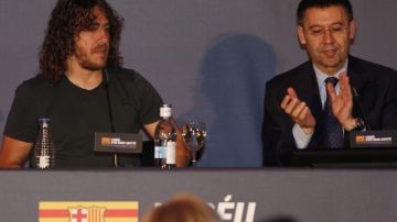 Carles Puyol (izq.) recibe el aplauso del presidente del Barcelona,  Josep María Bartomeu, en la conferencia de prensa de ayer.