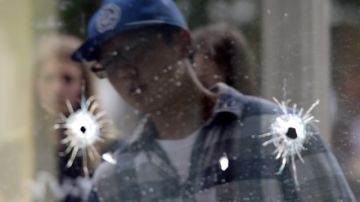 La imagen de un estudiante es reflejada en la vidriera del Isla Vista Deli Mart perforada por los disparos.