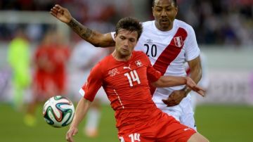 El jugador de  Suiza Valentin Stocker (izq.) disputa el balón con el peruano Luis Ramírez en el Estadio Swissporarena.