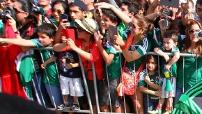 Andrés Guardado estampa su firma en un álbum de estampitas antes de que México iniciara la práctica en Santos.
