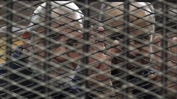 El líder de los Hermanos Musulmanes, Mohamed Badie, quien está entre los condenados a muerte, hace la señal de los cuatro dedos, durante un juicio en El Cairo, Egipto.