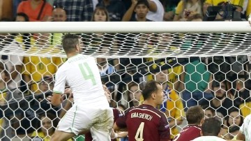 Islam Slimani (der.) remata de cabeza para anotar el gol que le dio a Argelia el empate contra Rusia en Curitiba.