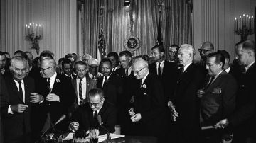 El presidente Lyndon Johnson firma la Ley de Derechos Civiles el 2 de julio de 1964. Detrás de él, Martin Luther King.