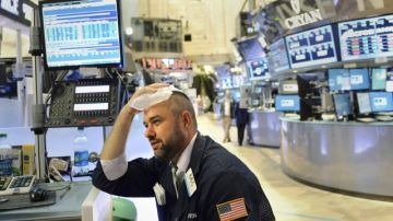 Un negociante con dolor de cabeza se pone hielo mientras trabaja en la Bolsa de Nueva York. Wall Street registró fuertes descensos y el indicador Dow Jones de Industriales cayó 1.8%.