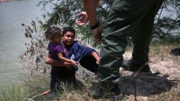 Un agente de la Patrulla Frontera ayuda a inmigrantes que cruzaron el Río Bravo, en Missiones, Texas, el 24 de julio de 2014.