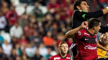 El arquero de Tigres,  Nahuel Guzmán, controla el balón ante  la mirada de uno de sus defensas y un delantero de Xolos