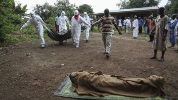 Enfermeros liberianos trasladan el cuerpo de una víctima del virus Ébola hasta un sitio para quemarlo, en la comunidad de Banjor.