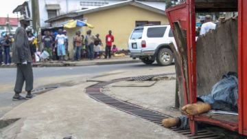 Habitantes de Monrovia observan el cadáver de una víctima de ébola en la calle.