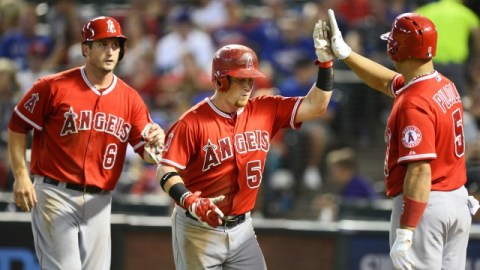 David Freese (6) y Albert Pujols (5) felicitan a Kole Calhoun (c), que conectó jonrón de tres carreras para los Angelinos contra los Rangers en Arlington, Texas.