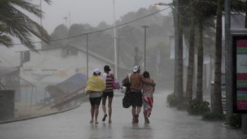 Un grupo de personas camina por una calle en el puerto mexicano de Acapulco ayer donde se registran fuertes lluvias generadas por la tormenta tropical "Marie".