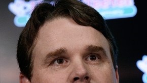 El coach de los Redskins, Jay Gruden, junto a un logo que podría desaparecer en la próxima temporada del fútbol americano profesional.