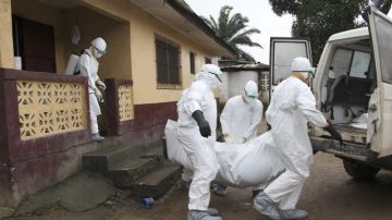 Enfermeros llevan el cuerpo de una víctima del ébola a las afueras de Monrovia, en Liberia.