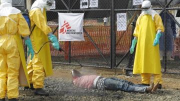 Un equipo de enfermeras liberianas desinfectan el cuerpo de una  persona que se sospecha fue infectada con el virus del ébola, en la entrada del centro de tratamiento de  Médicos Sin Fronteras (MSF),   en Monrovia, Liberia.