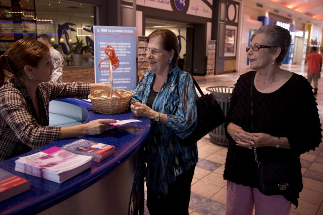 Dos señoras recogen un folleto del Departamento de Salud sobre una campaña contra el sida en Puerto Rico.