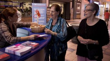 Dos señoras recogen un folleto del Departamento de Salud sobre una campaña contra el sida en Puerto Rico.