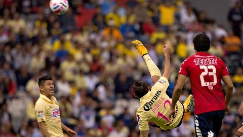 El jugador del América, Pablo Aguilar, se tiende en el aire para rematar un balón.