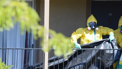 miembros de un equipo especial de limpieza  cuelgan  plástico para cubrir la puerta de entrada del apartamento donde el paciente con ébola se alojaba en Dallas, Texas.