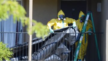 miembros de un equipo especial de limpieza  cuelgan  plástico para cubrir la puerta de entrada del apartamento donde el paciente con ébola se alojaba en Dallas, Texas.
