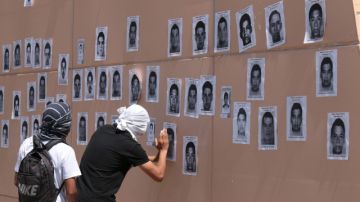 Estudiantes pegan retratos de los 43  desaparecidos.