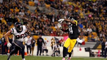 El receptor Antonio Brown, perseguido por J.J. Watt, lanza un pase de touchdown para los Steelers al final del segundo periodo en la jugada del partido.