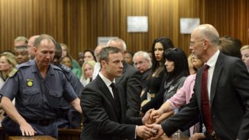 Policías escoltan a Oscar Pistorius (c) quien se despide de sus familiares antes de ser trasladado a  la cárcel    para purgar cinco años por matar a su novia Reeva Steenkamp.