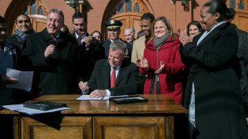 El Alcalde, junto a la presidenta del Concejo (der.), y otros asistentes, firmó las leyes en Queens.