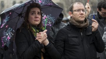 Dos ciudadanos sostienen simbólicamente lapiceros y bolígrafos mientras guarda un minuto de silencio ante la catedral de Notre Dame ayer en París.
