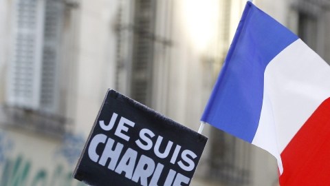Un hombre con un cartel con el eslogan 'Je Suis Charlie'  la bandera francesa participa en una de las múltiples manifestaciones realizadas ayer Francia.