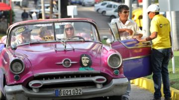 Un grupo de turistas espera en un vehículo clásico  en La Habana.