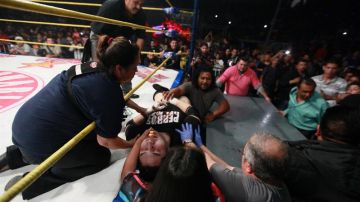 El luchador mexicano "El Hijo del Perro" Aguayo" (c) recibe atención tras recibir una patada voladora de su rival, Rey Misterio.
