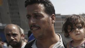 Refugees, mostly from Syria, wait for a bus after disembarking at the port of Piraeus, near Athens, Greece.