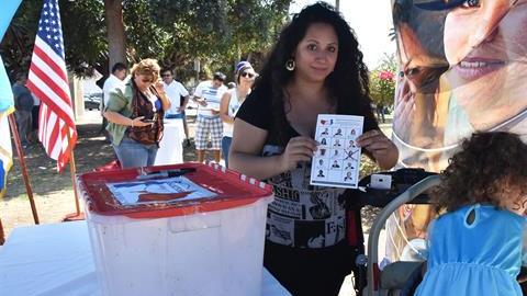 Maya Batres (i) muestra su papeleta electoral en las elecciones presidenciales simbólicas de la comunidad guatemalteca en Estados Unidos, en Los Ángeles, California